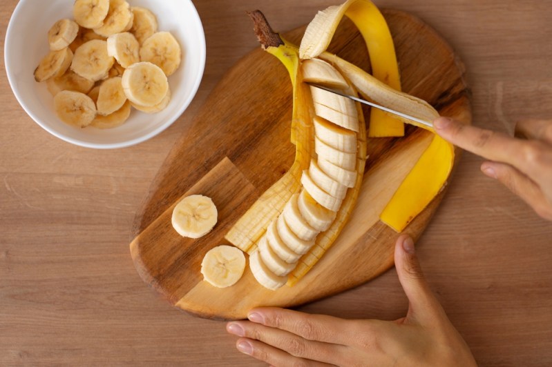 Person slicing a ripe banana