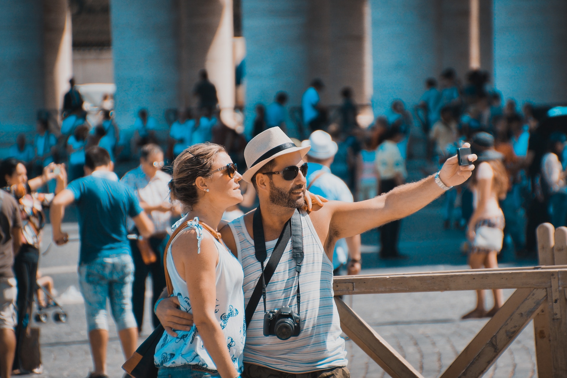 A couple taking a selfie at a busy tourist spot.