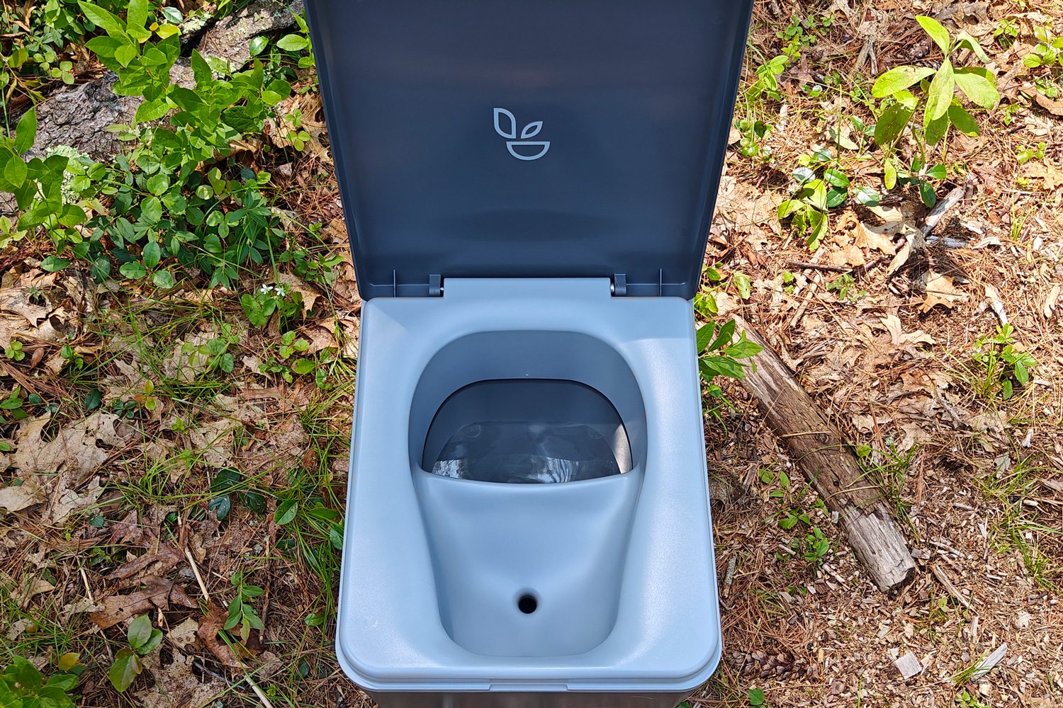Trelino Evo S portable composting toilet with lid open in the woods.