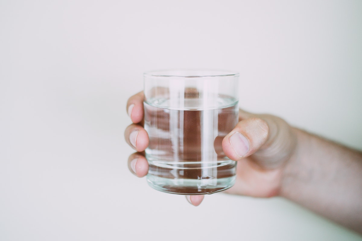 A person holding a small cup of water