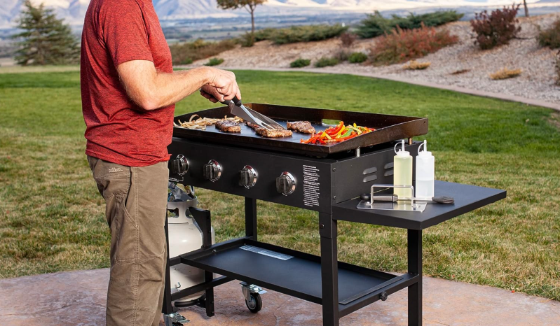A man using the Blackstone 36-inch Gas Griddle Cooking Station in a yard.