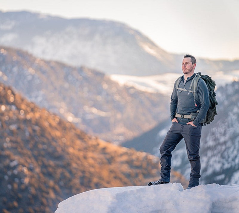 Man at the top of a mountain wearing a Merino wool sweater