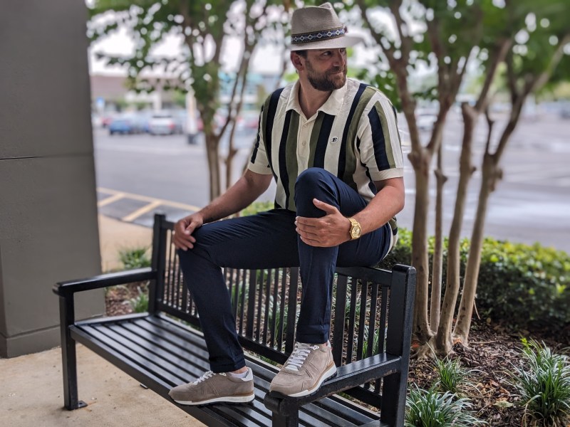 Man on a bench wearing a hat and polo