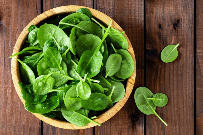Fresh spinach leaves on wooden background. Healthy vegan food. Top view