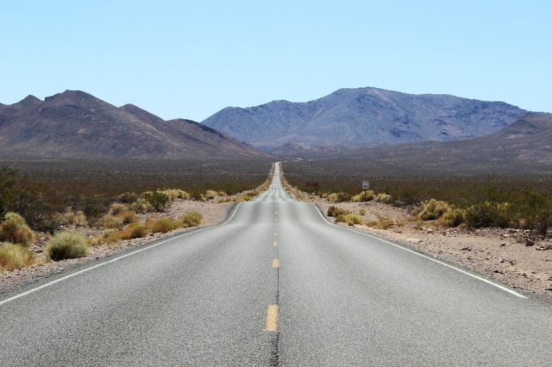 Isolated stretch of highway in Death Valley with mountains in the background