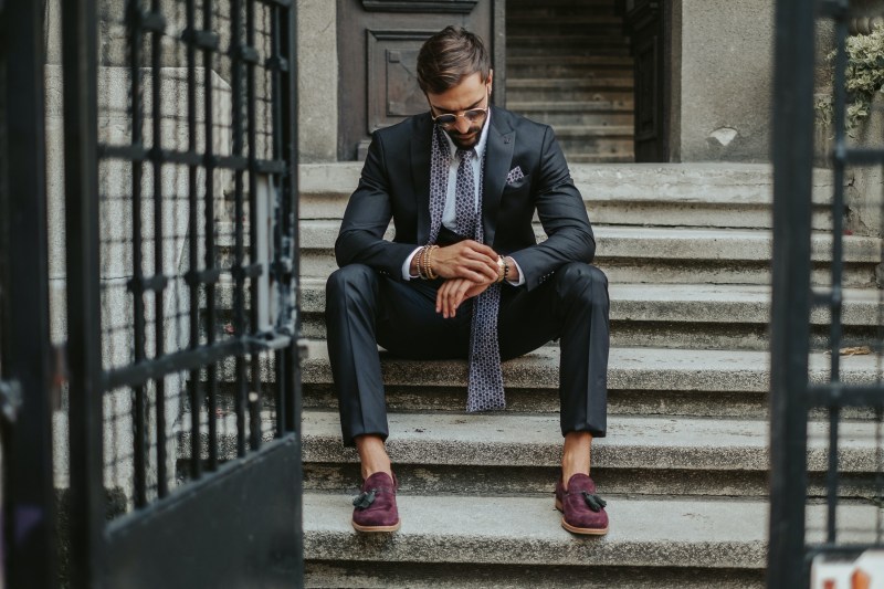 businessman waiting on the stairs in daytime and looking at the time