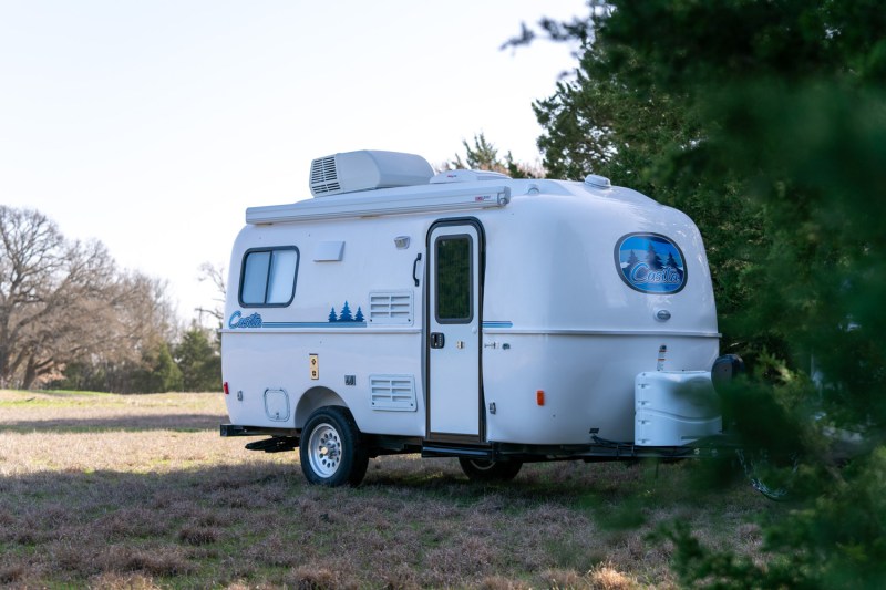 Casita Travel Trailer set up near a bunch of trees.