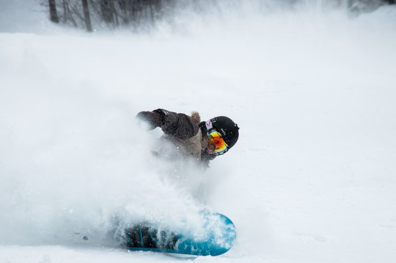 A snowboarder sprays snow into the air.