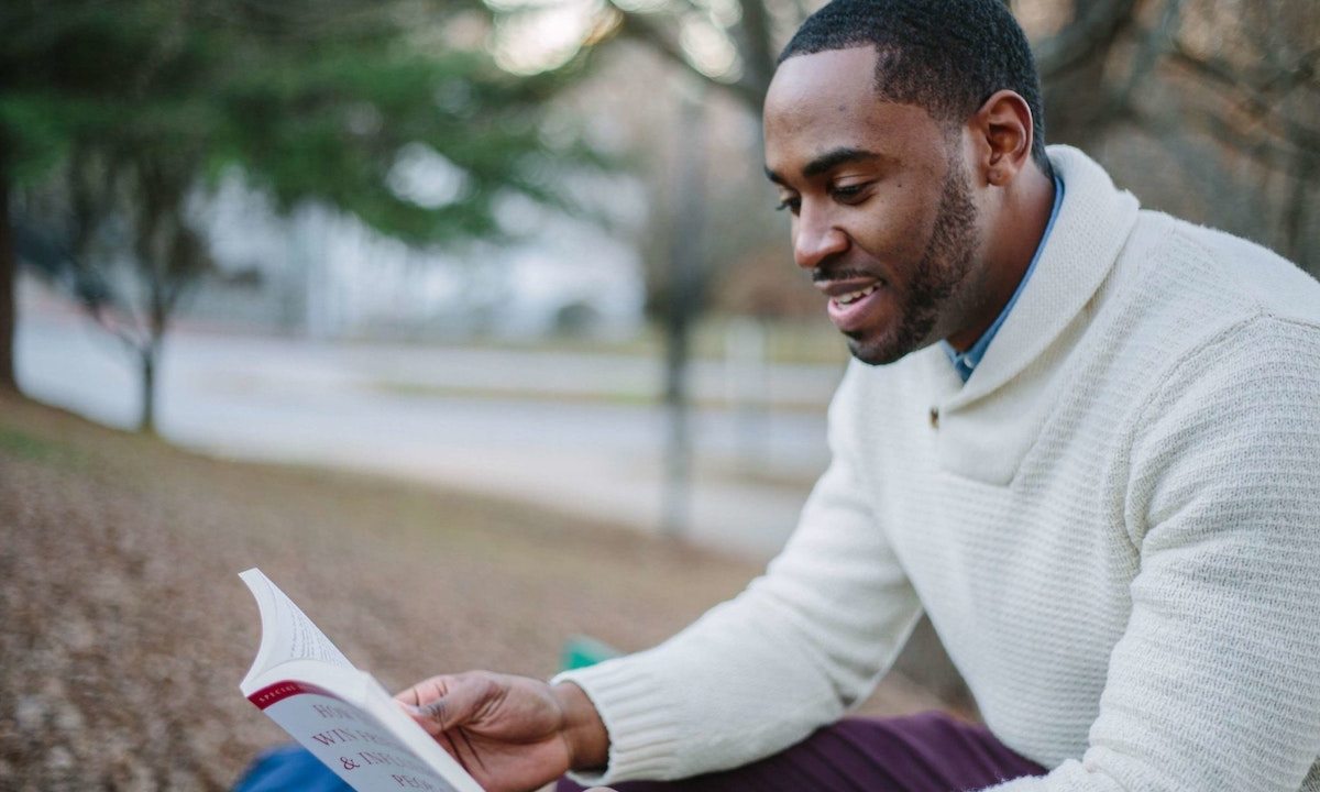 A man reading a book while sitting outside
