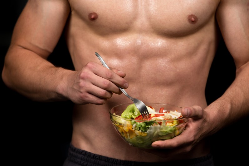 Shaped and healthy body building man holding a fresh salad bowl,shaped abdominal