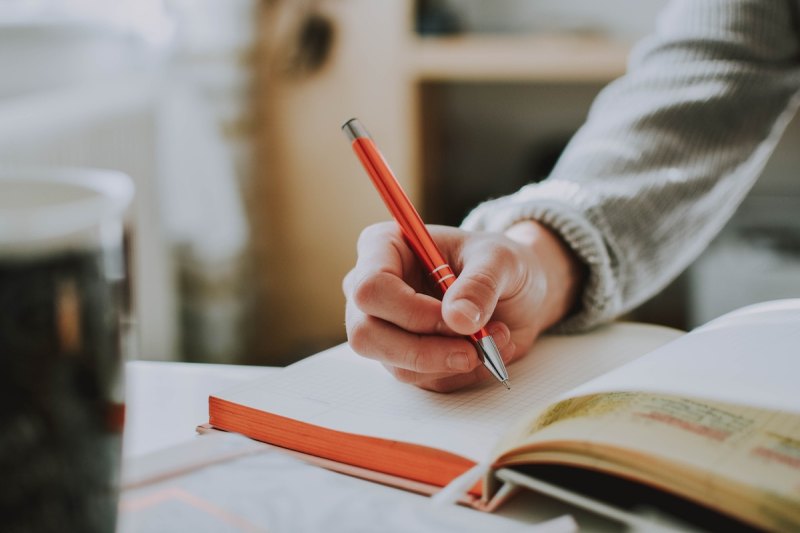 a person with a gray sweater writing with a pen