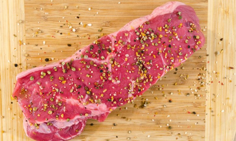 Raw, seasoned steak on cutting board