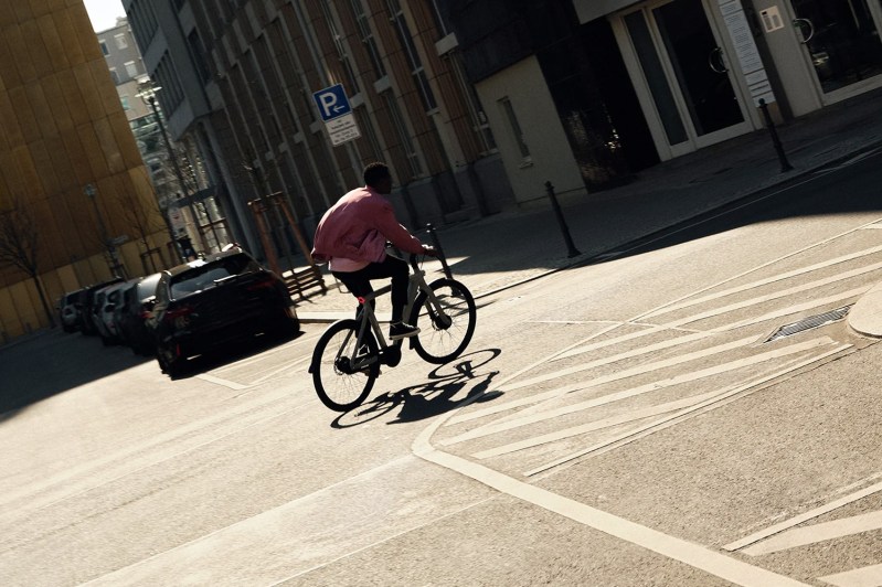 Man riding through city streets on a VanMoof electric bike/ebike.