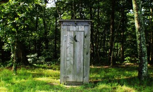 A wooden outhouse with a crescent moon cutout on the door.