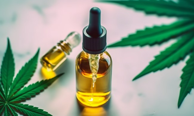 Medical CBD oil on dark background with cannabis leaves