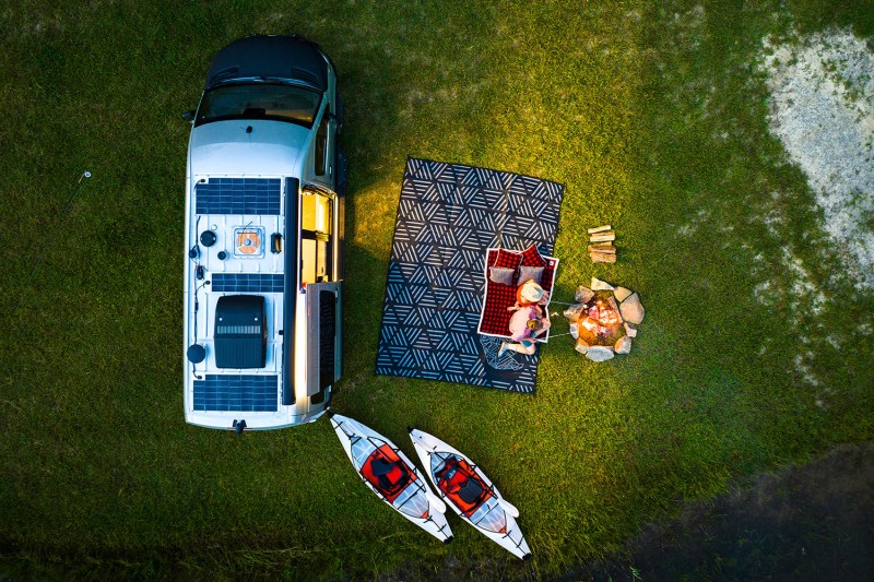 Aerial view of a couple relaxing on an outdoor blanket beside an Airstream Interstate 19X Touring Coach.