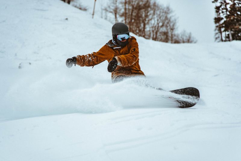A man on a snowboard rips a turn in soft snow.