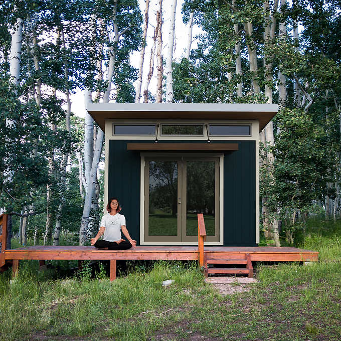 A person doing yoga outside of a she shed.