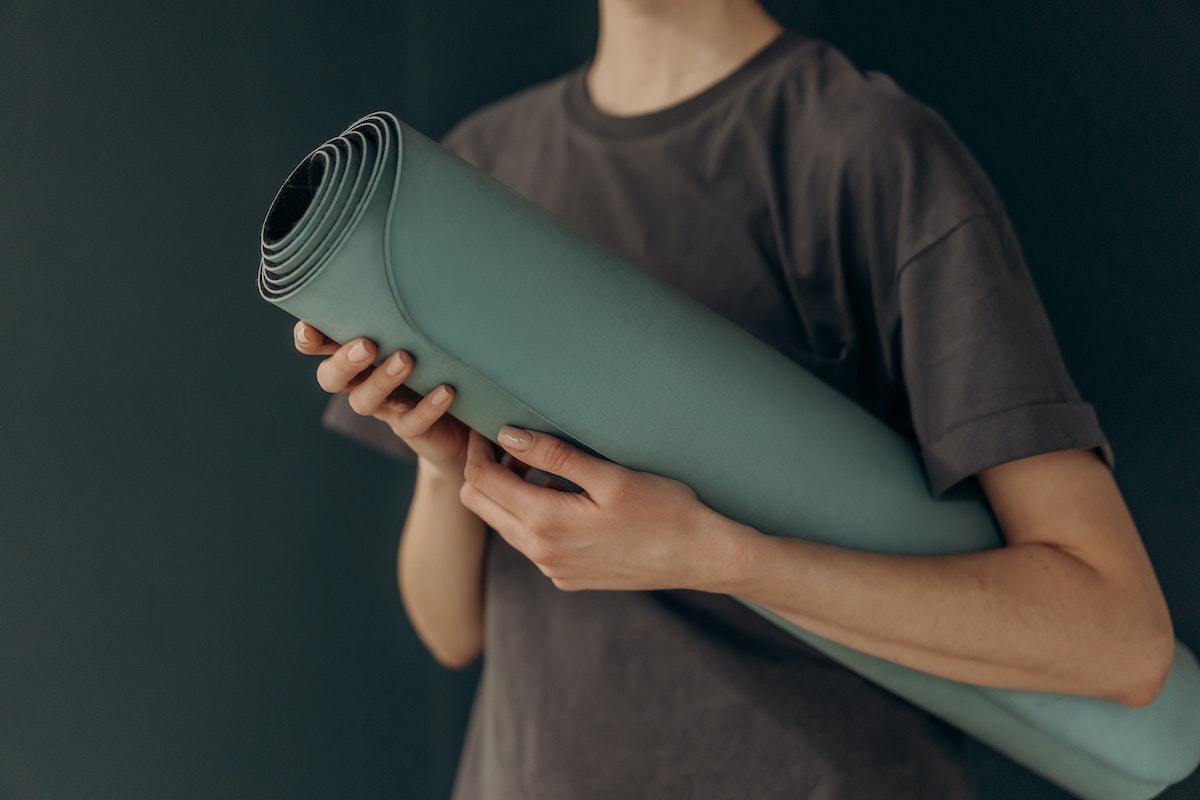 a man holding a green yoga mat