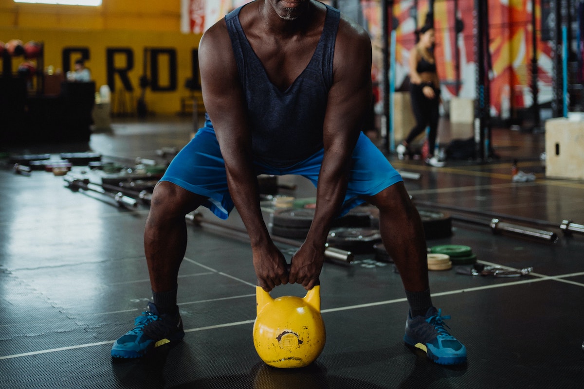 Man with yellow kettlebell squatting
