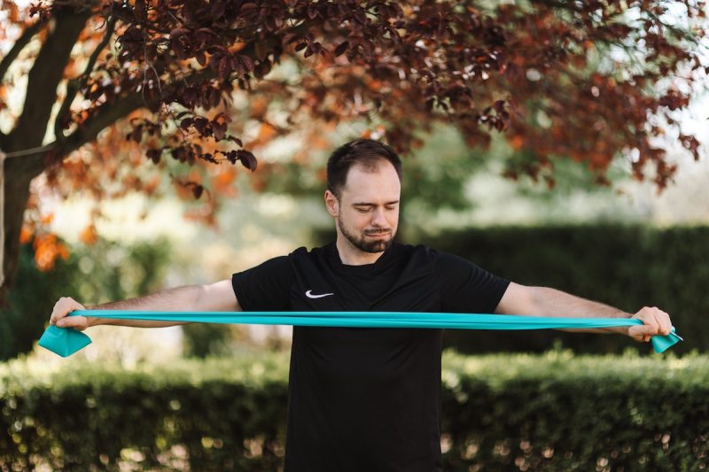 Man using a teal resistance band outside