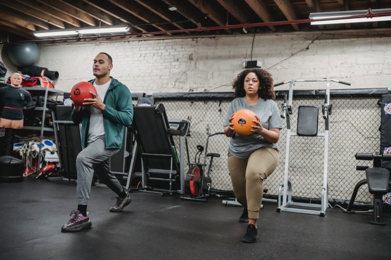 two people doing a lunge with medicine ball