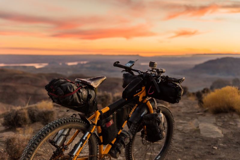 Bikepacking bike parked in a rugged desert landscape at sunrise.