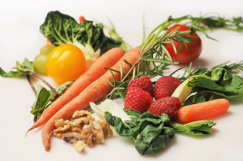Carrots, raspberries, walnuts, and leafy greens on surface