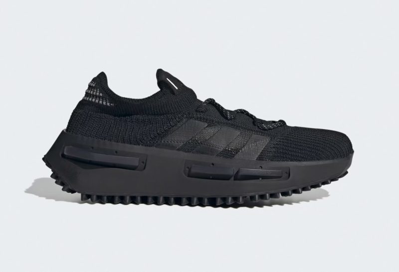 A side angle of the Adidas NMD_S1 shoes in black against a gray background.