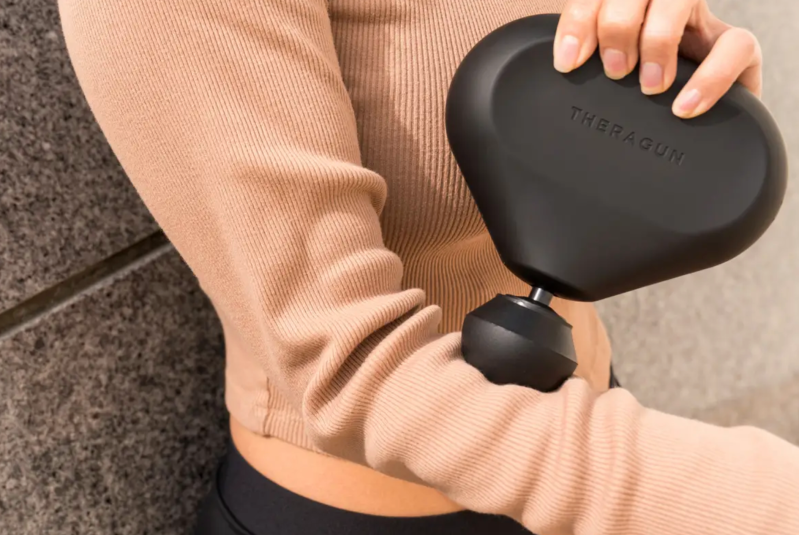 Someone using the Theragun Mini on their chest.