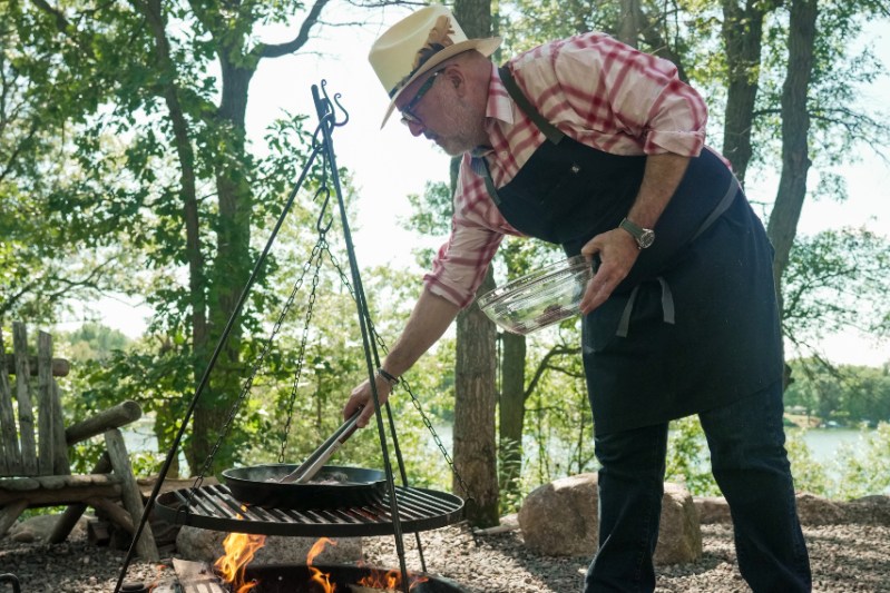 Andrew Zimmern cooking over fire.