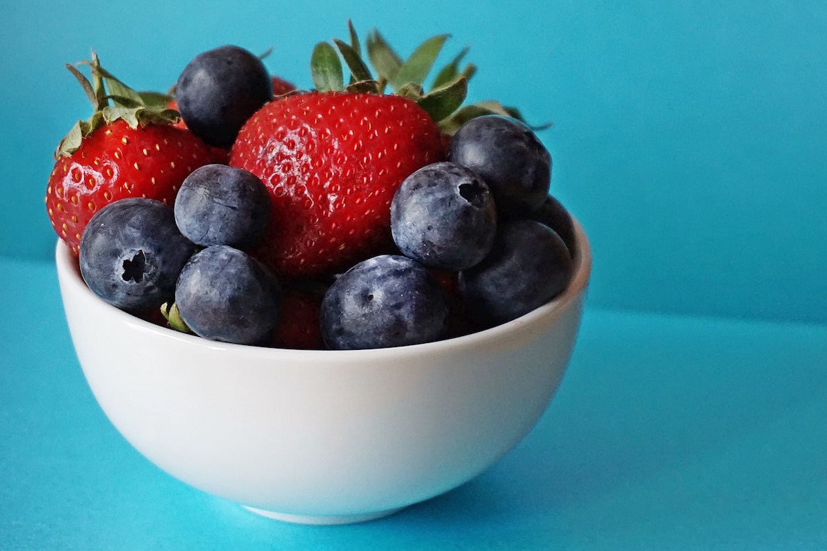 A bowl of berries on blue background