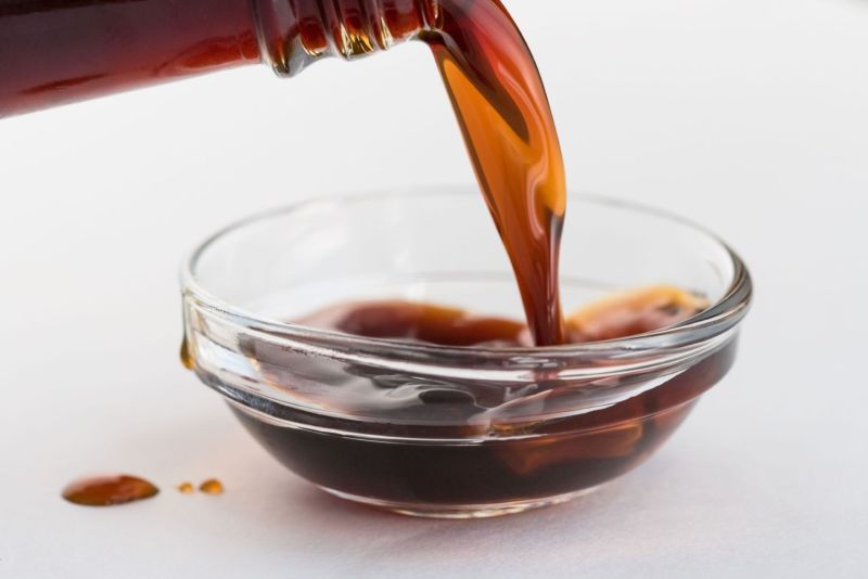 Pouring coconut aminos in clear glass bowl