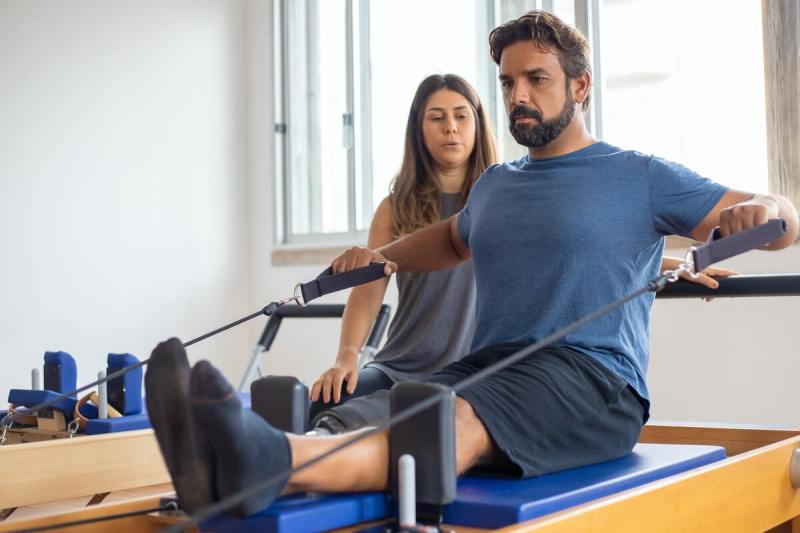 Man using Pilates reformer.