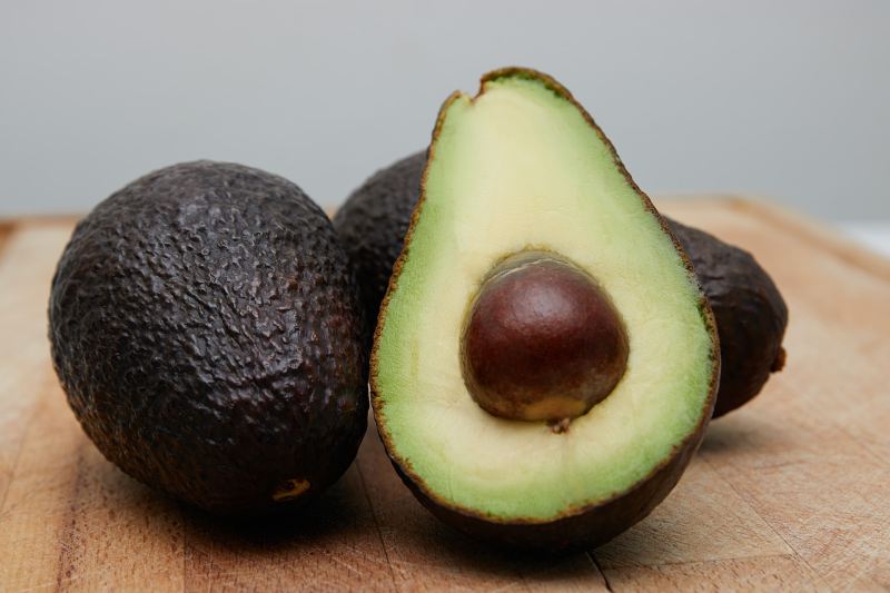 A ripe avocado on a wooden cutting board.