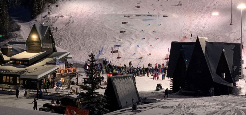 Skiers and snowboarders riding under the alpenglow.