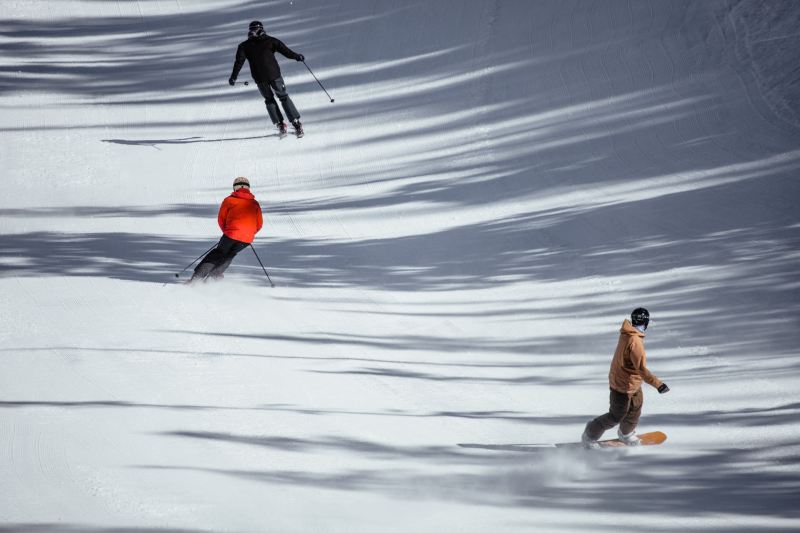 Skiers and snowboarders ride down the mountain