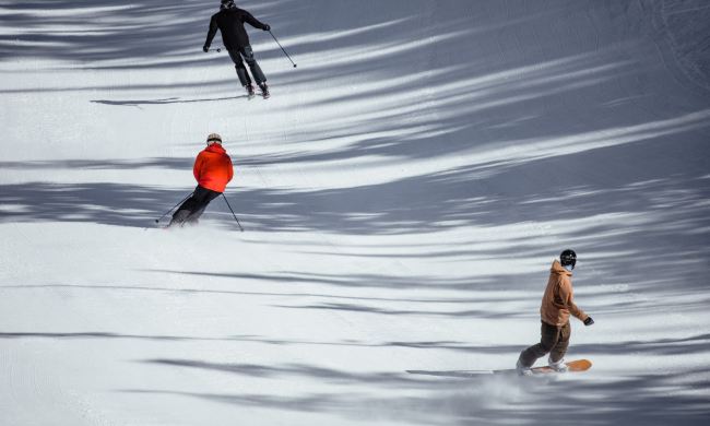 Skiers and snowboarders ride down the mountain