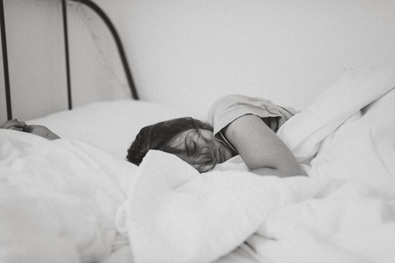 Woman tired laying on bed sleeping black and white