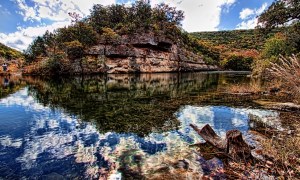A beautiful view of Lost Maples State Park with Limestone bluffs along a clear river with a vivid reflection