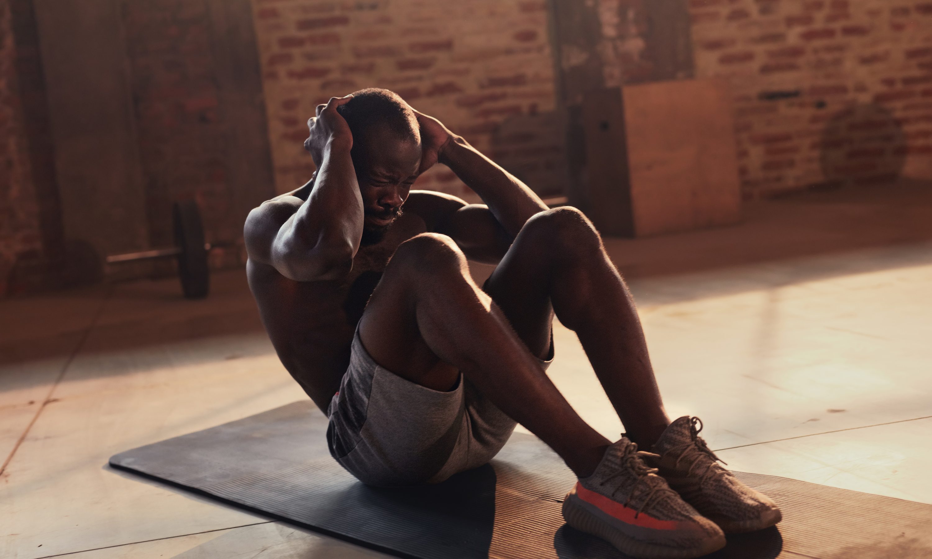 Sport man doing abs crunches exercise, fitness workout at gym. Black male athlete exercising on yoga mat, doing abdomen muscle training indoors