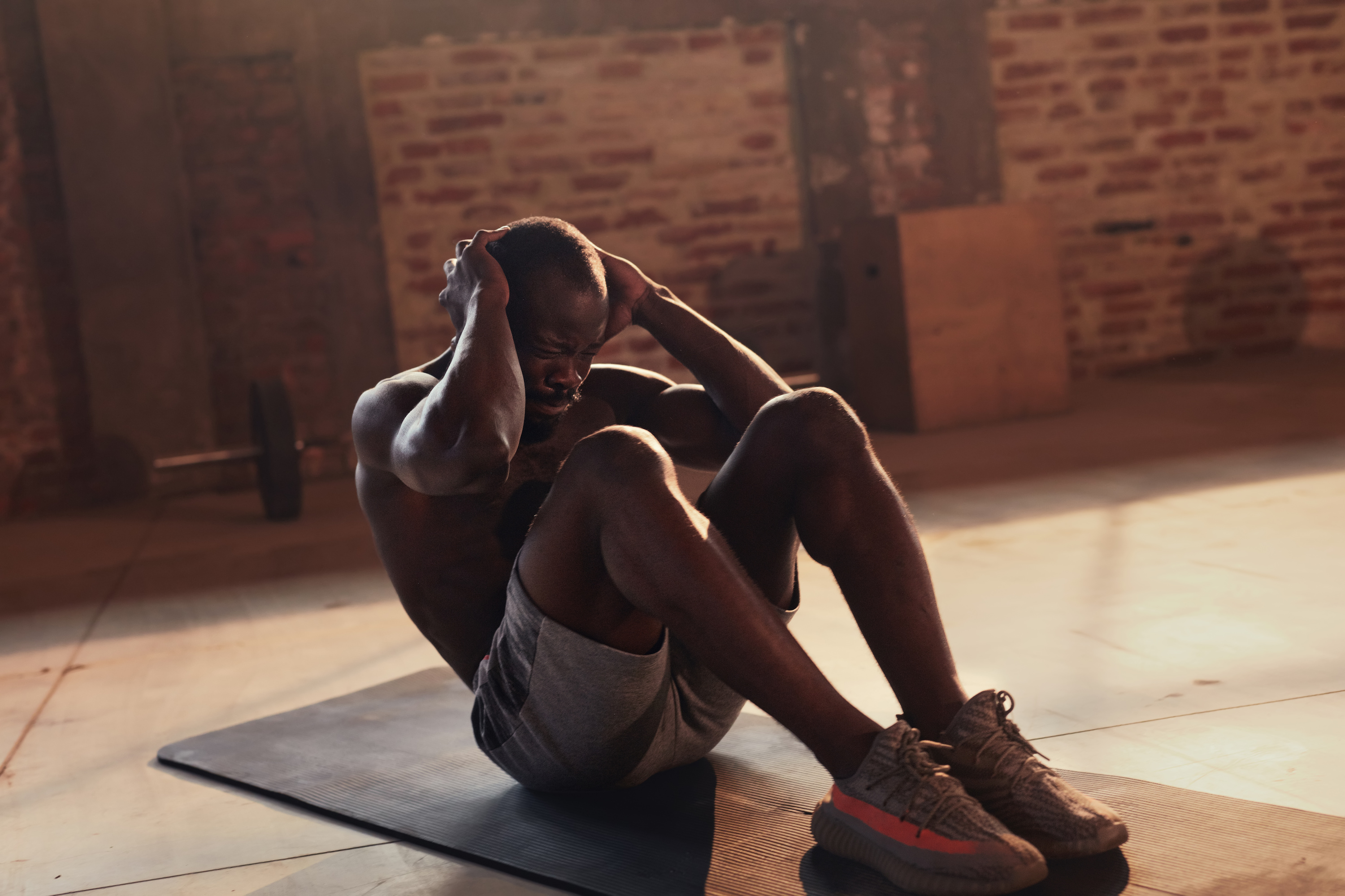 Sport man doing abs crunches exercise, fitness workout at gym. Black male athlete exercising on yoga mat, doing abdomen muscle training indoors