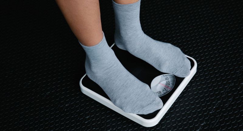 Man in gray socks looking at scale