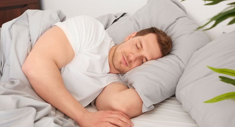 man sleeping soundly in a white t-shirt