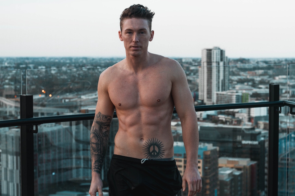 a shirtless man standing on a rooftop in a city