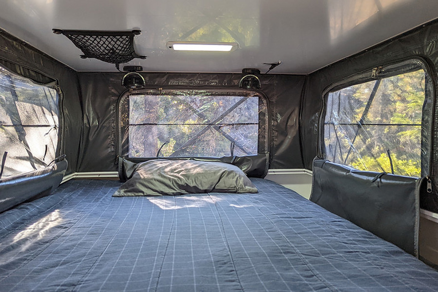 Bed in the pop-up camper top of Optimized Overlanding's overland trailer.
