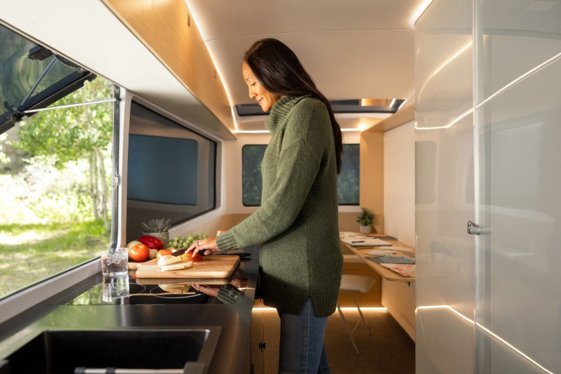 A young woman using the kitchen inside the Pebble Life electric travel trailer.
