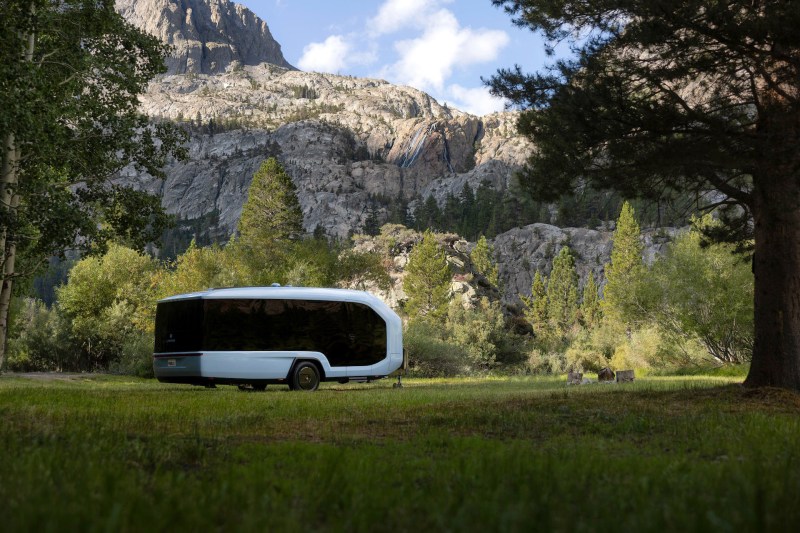 Pebble electric RV travel trailer in a grassy field in the mountains.
