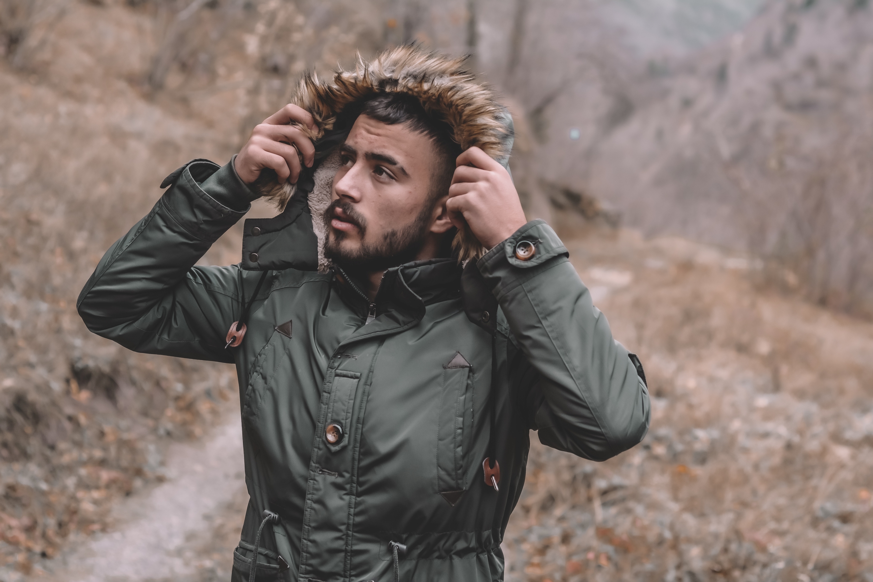 Man in the woods lifting his hood up