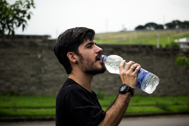 man drinking water outside